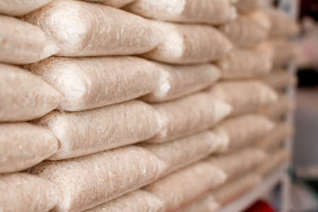 Rice. Stacking of clear bags of white rice. Rice store. Agricultural sector in the farm. Stacked of Rice bags in shop.の写真素材