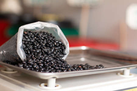 Bag of spilled black beans. Black beans on digital scale. Details of black beans. Ceco bean trade.の写真素材