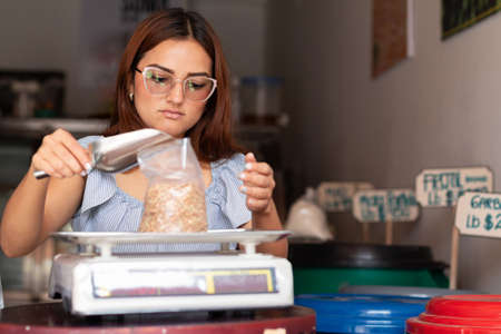 Woman packing lentils with metal spoon. Loose products.の写真素材