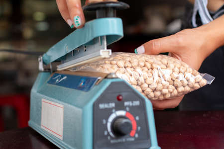 Hands of a young woman using plastic bag sealing machine. Plastic Film sealer machine. Concept of urban, manual and simple works.の写真素材
