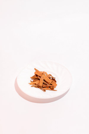 Split cinnamon for cooking stacked on white background. Pile of cinnamon on small plate.の写真素材