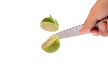Hand with knife cutting lime in half in the air. clipping path., full depth of field.