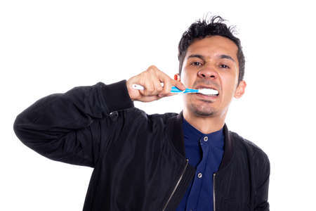 Man brushing his mouth isolated on white background. Young latin guy brushing his mouth in front of camera.の写真素材