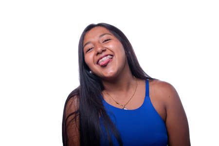 Dark skinned woman sticking out her tongue, isolated on white background. Portrait of a young latin woman gesticulating with tongue. Happiness expression. Woman of latin, indigenous or mixed ethnicityの写真素材