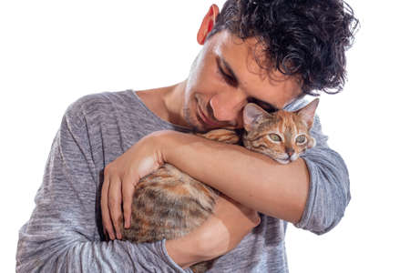 Man hugging his cat, isolated on white background. Young adult who missed his pet hugs her with much love.の写真素材