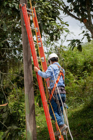 Male electrician coming down the stairs after finishing his work. Descending from a light pole.