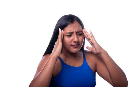 Black-skinned latin woman has a bad headache. Black girl touches her head with her hands because she feels pain, isolated in a totally white background.の写真素材
