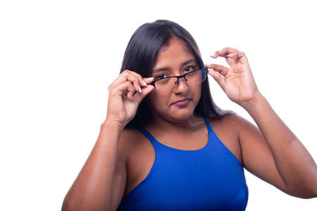 Black skinned latin woman lowers her glasses with accepting expression, isolated on white background. Face expressions.の写真素材
