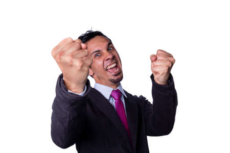 Businessman celebrating a victory by raising his fists and giving a big shout while looking at the camera, isolated on a white background. Young adult latin.の写真素材