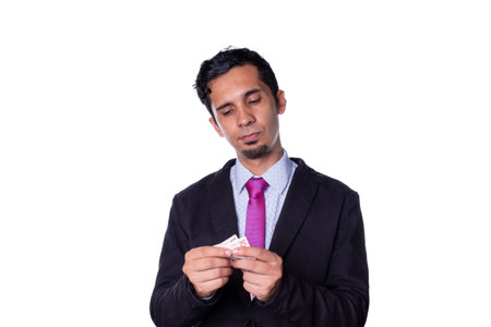 Businessman counting money with his hands. Young latin adult young man with serious look looking at cash money, isolated on all white background.の写真素材