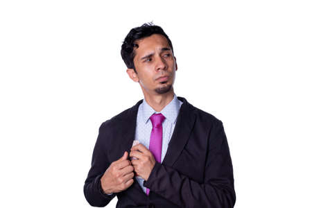 Businessman secretly taking money. Young adult young man dressed in elegant clothes keeps money in his sack with suspicious look, isolated on all-white background.の写真素材