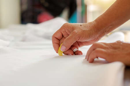 Female dressmakers hands marking fabric for clothing design. Sewing work and clothing design.の写真素材