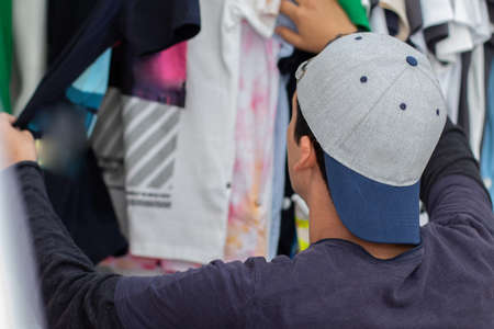Young latin man wearing a youth cap shopping for clothes.の写真素材