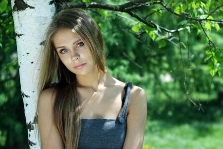 Portrait of the young beautiful girl on a background of leaves of a birch の写真素材