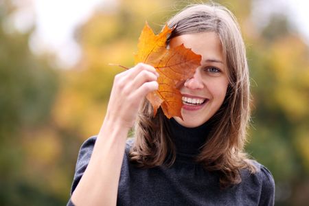 Beautiful romantic brunette with golden autumn leaf 