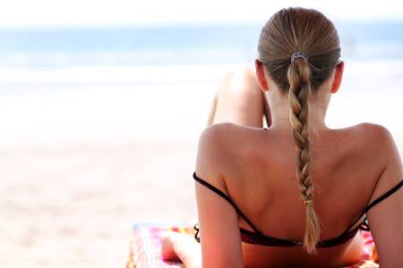 young woman sunbathes lying on chaise loungesの写真素材