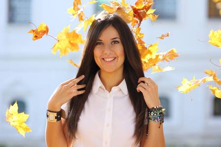 Portrait of a happy woman against yellow leavesの写真素材