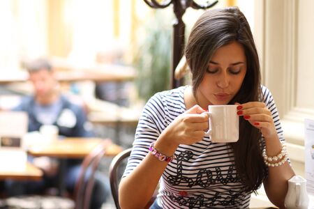 Beautiful young girl sipping coffee の写真素材