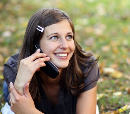 woman calling by phone in autumn park の写真素材