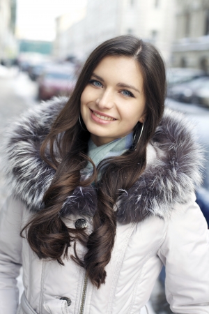Caucasian young adult female smiling and walking down snow covered streetの写真素材