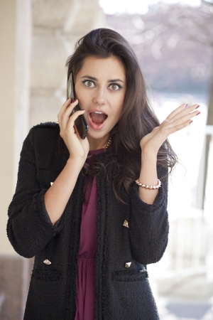 Young happy woman calling by phone on the streetの写真素材