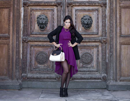 Young beautiful woman in a burgundy dress on a background of wooden gatesの写真素材
