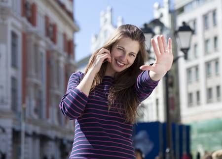 Young happy woman calling by phone on the streetの写真素材