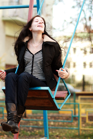 Young woman wearing sitting on a swing in a parkの写真素材