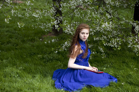 Beautiful young woman on the green grass in the parkの写真素材