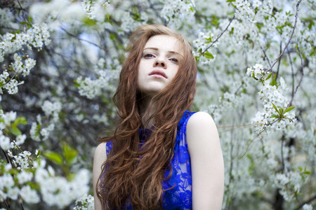 Portrait of Beautiful young woman standing near blooming trees in spring garden の写真素材