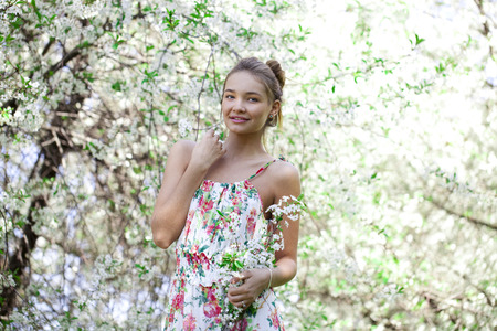 Portrait of Beautiful young woman standing near blooming trees in spring garden の写真素材