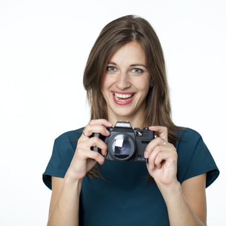 Happy young woman using a camera to take photo, isolated on whiteの写真素材