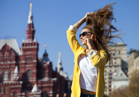 Happy beautiful woman calling by phone in autumn streetの写真素材