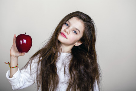 Portrait of a beautiful little girl holding a red apple, isolated on white backgroundの写真素材