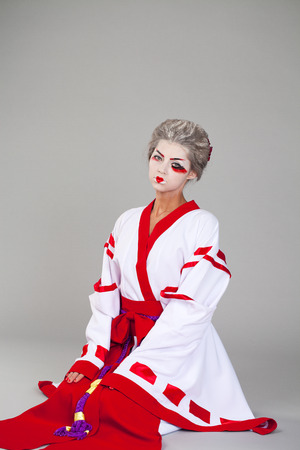 Beautiful young woman in white kimono dress on gray backgroundの写真素材