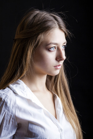 Portrait of beautiful young woman in white shirt, isolated on black backgroundの写真素材