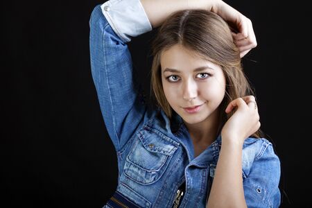 Portrait young girl in a blue jeans jacket, isolated on black backgroundの写真素材