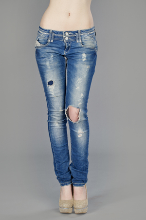 Close up of a beautiful woman wearing jeans isolated on gray backgroundの写真素材