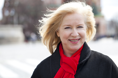 Happy portrait of an elderly blonde woman, spring on the street