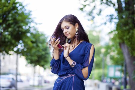 Young woman reading a message on the phone in a summer parkの写真素材