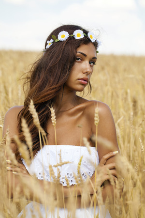 Close up portrait of a beautiful young brunette woman in a wheat fieldの写真素材