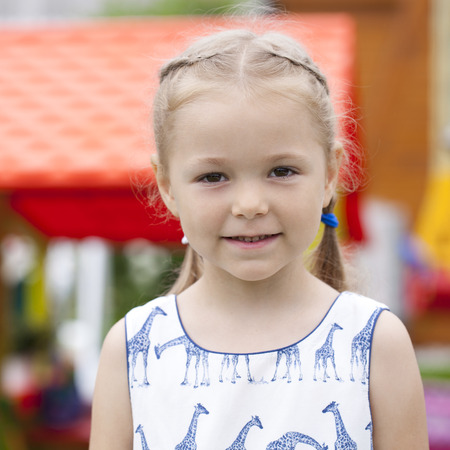 Portrait of beautiful happy little girl, against background of summer parkの写真素材