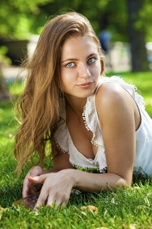 Close up Portrait, Young beautiful blonde woman posing outdoors in summer green parkの写真素材
