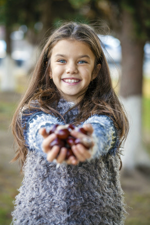 Close up portrait of a beautiful nine year old little girl in autumn parkの写真素材