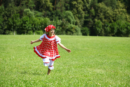 Little girl in a red polka-dot sundress into a major run on green fieldの写真素材