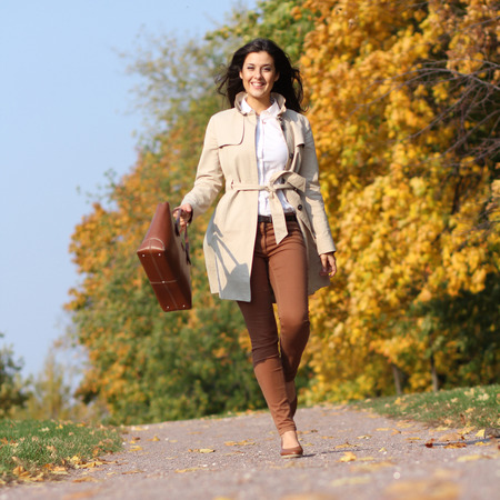 Full length, walking woman in autumn parkの写真素材