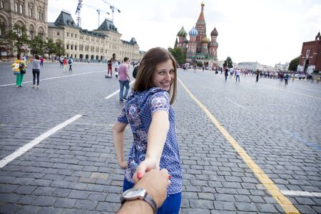 Follow me. Young happy girl pulls the guys hand on the Red Square in Moscow, Russia