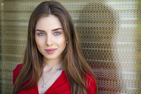 Close up portrait of a beautiful young girl in red shirt on the background of the urban landscapeの写真素材
