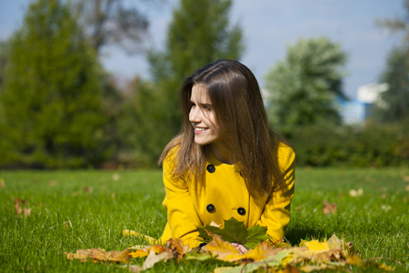 Beautiful young woman in yellow coat in autumn streetの写真素材