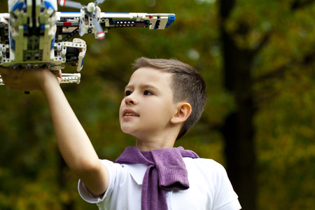 Portrait of a pretty brunette little Boy holds plastic model airplane in autumn parkの写真素材